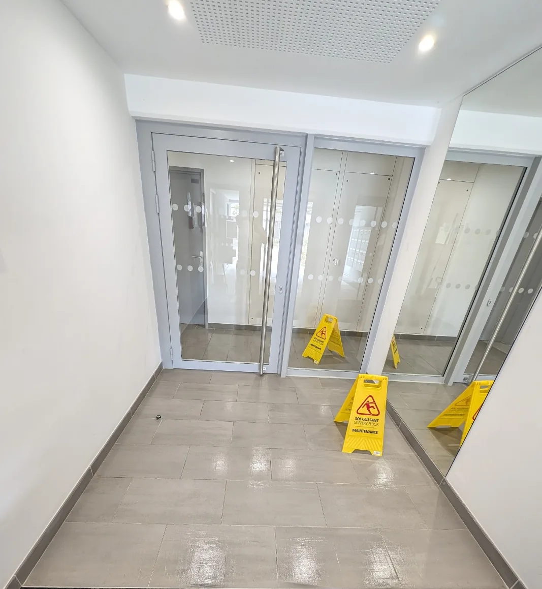 Sas d'entrée d'une copropriété à Nantes pendant le nettoyage, sol carrelé et portes vitrées